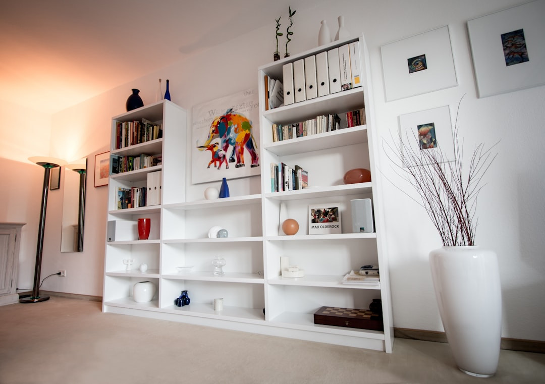 bespoke white bookshelves conatining books, with coloured wall art in the middle