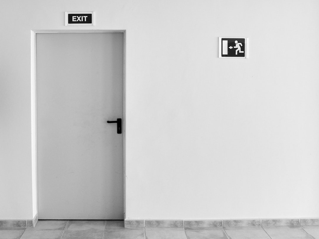 a white fire door with black signage set in a white wall